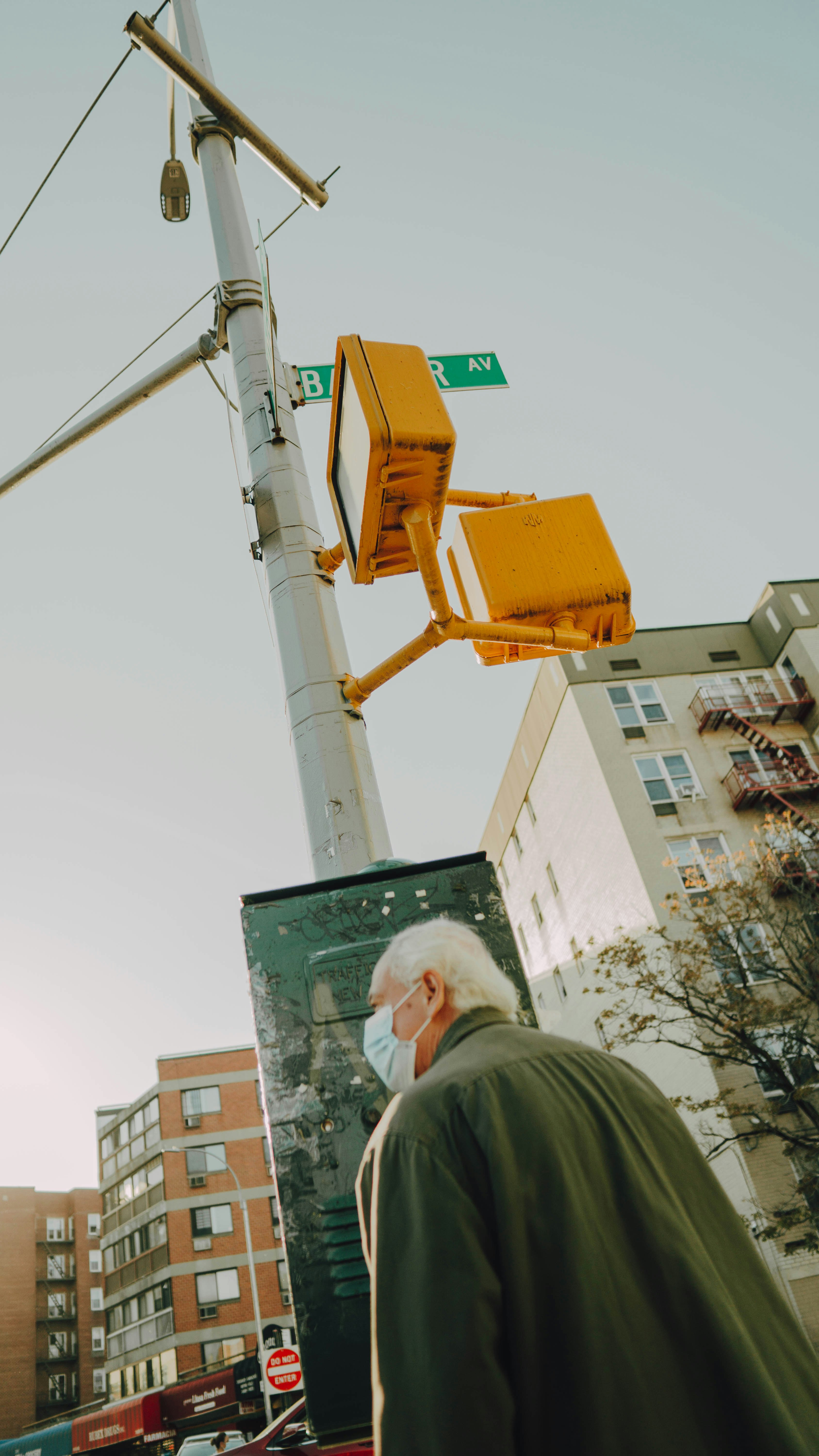 man in green jacket standing near green and white signage during daytime